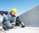 Workers installing a new flat roof membrane on a modern building